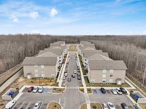A parking lot is in front of a building with a long row of houses on either side.