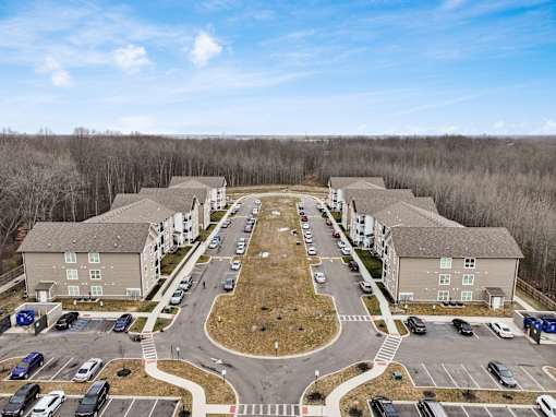 A large apartment complex with a parking lot in front.