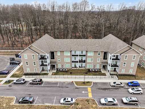 Apartment complex with a parking lot in front.
