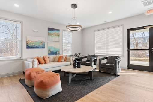 A living room with a white couch, orange pillows, and a grey rug.