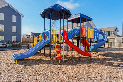 A playground with a blue slide and yellow and red slides.