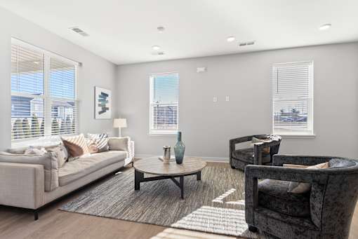 A living room with a grey couch, a coffee table, and a chair.
