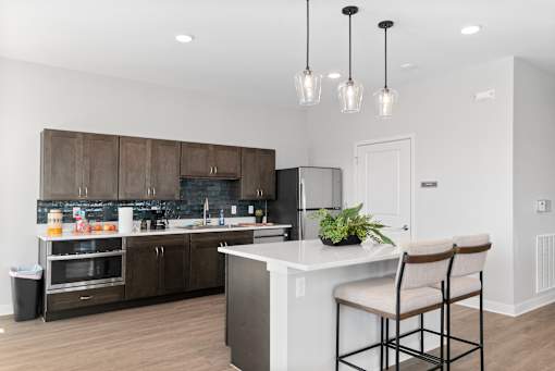 A kitchen with a white island and brown chairs.