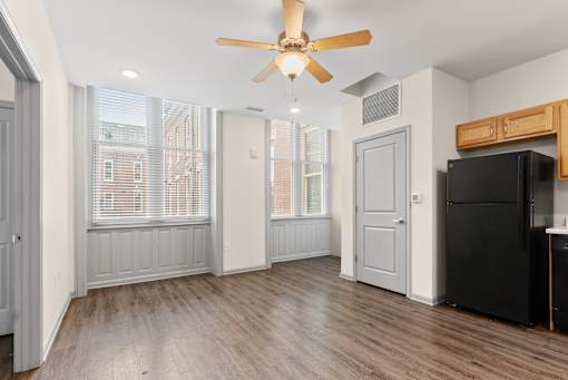 A room with a ceiling fan and a black refrigerator.