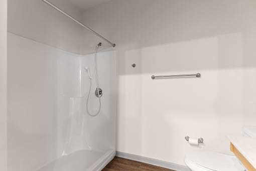 A white bathroom with a shower, toilet, and sink.