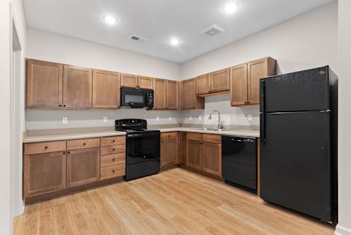 A kitchen with black appliances and wooden cabinets.