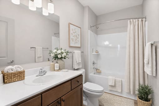 A bathroom with a white sink, toilet, and shower area.