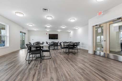 a conference room with tables and chairs and a tv on the wall