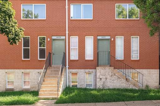 A red brick building with green doors and windows.
