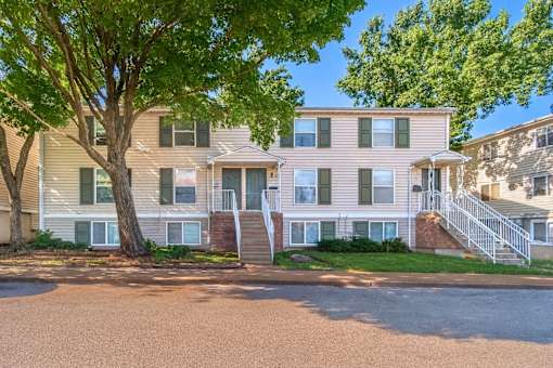 A two-story apartment building with a tree in front.