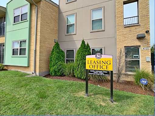 A leasing office sign is posted in front of a building.