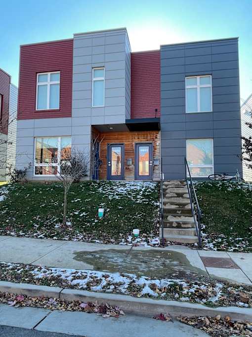 A modern house with a red and grey exterior and a wooden front door.