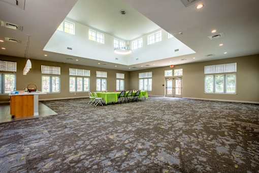 A room with a carpeted floor and a table with chairs in it.