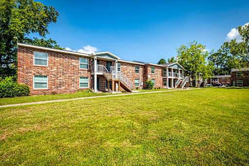 A brick apartment building with a green lawn in front.