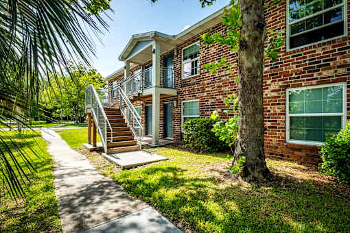 A red brick house with a tree in front.