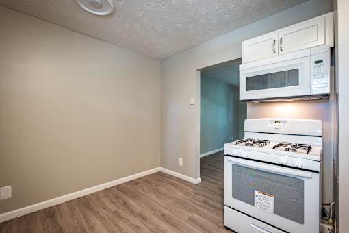 A kitchen with a white oven and microwave above it.
