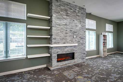 A stone fireplace with a fire going in it.