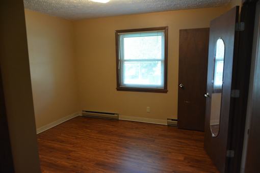 an empty living room with wood floors and a window