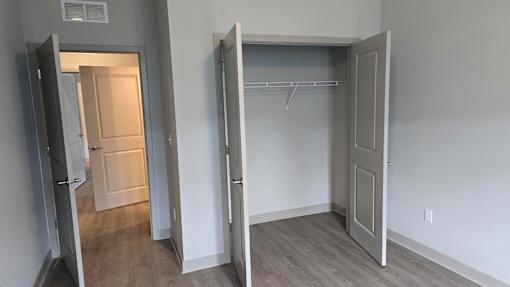 A room with a white door and a white closet with a shelf.