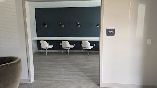 A room with a black wall and four white chairs.