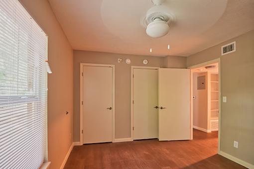 A room with a white ceiling fan and three white doors.