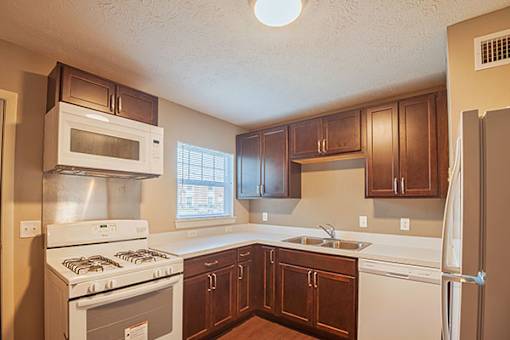 A kitchen with brown cabinets and white appliances.