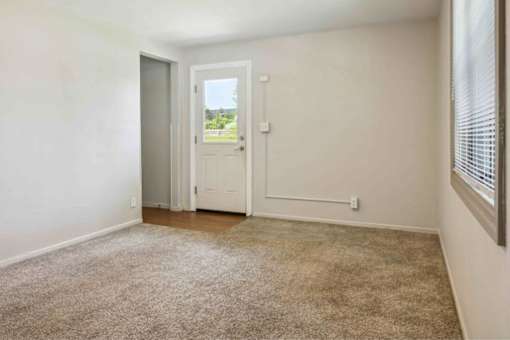 A room with a carpeted floor and a door leading outside.