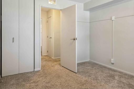 A white door is open in a room with a carpeted floor.