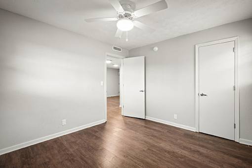 A room with a ceiling fan and three doors.
