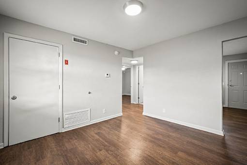 A room with a white door and a white wall with a mirror on the wall.