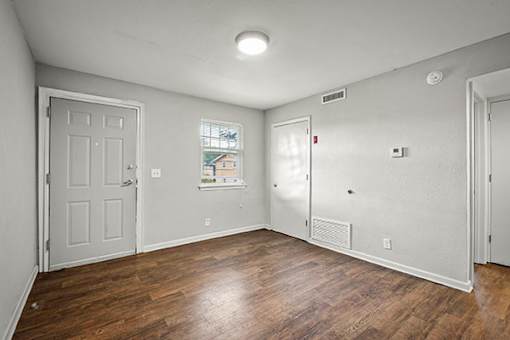 A room with a white door and a window with a view of a house.