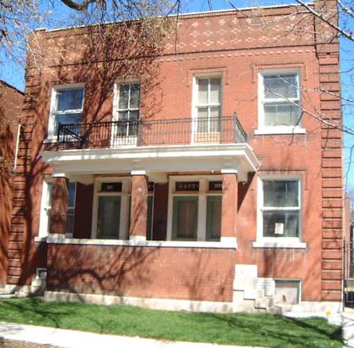 A red brick building with a balcony on the second floor.