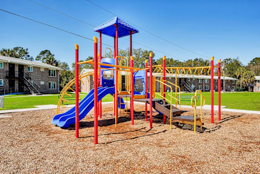 A playground with a blue slide and yellow and red structures.