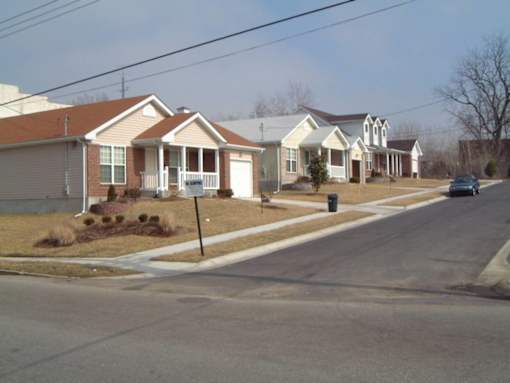 A street view of a residential area with houses and a car parked on the side.