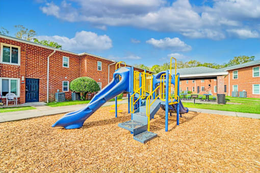 A playground with a blue slide and yellow railing.