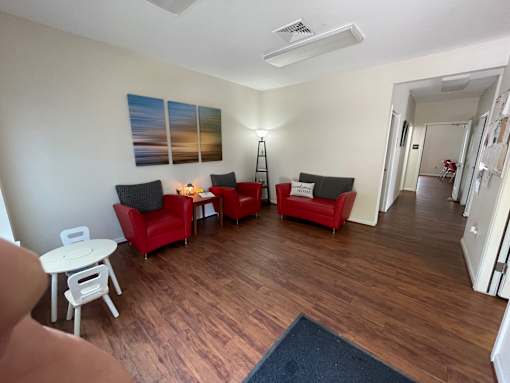 A living room with red chairs and a white table.