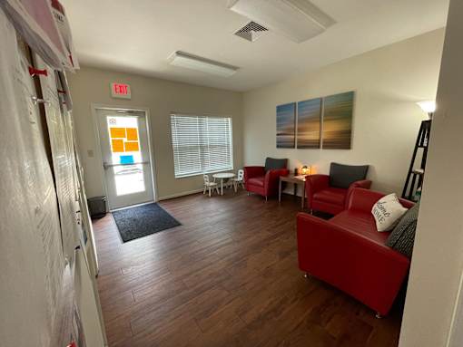 A room with a red couch and a black rug.