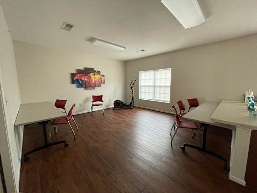 A room with a white table and red chairs.