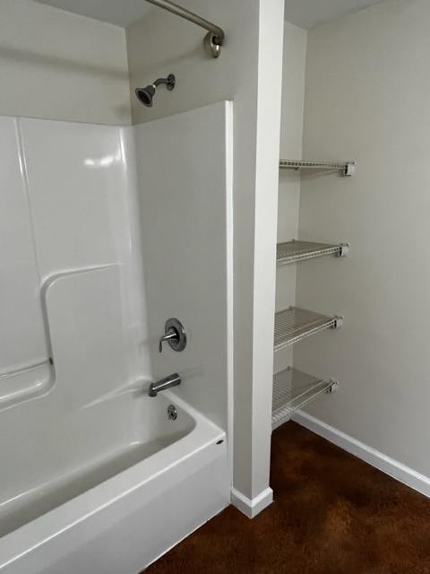 A white bathtub with a shower head and faucet.
