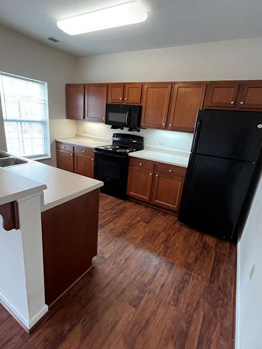 A kitchen with wooden cabinets and a black fridge.