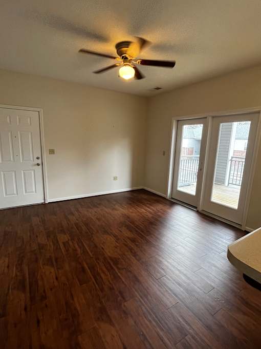 A ceiling fan hangs over a wooden floor in a room with a skylight.