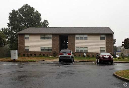 an apartment building with cars parked in a parking lot