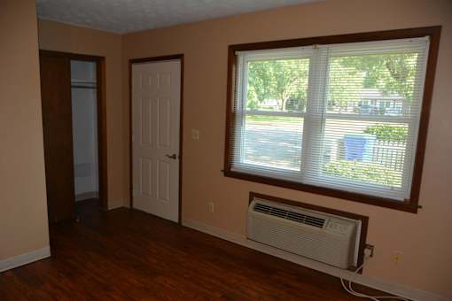 an empty living room with a window and a air conditioner