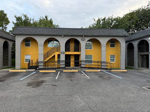 A parking lot with a yellow building and a black gate.