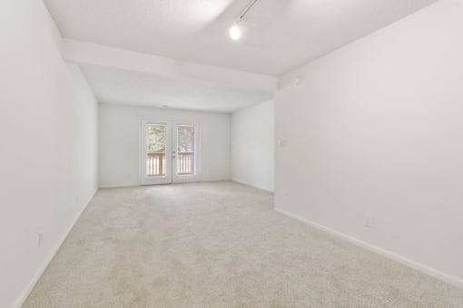 a spacious living room with white walls and carpet