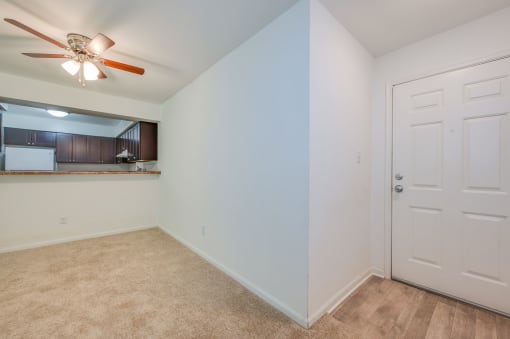 a living room with a ceiling fan and a door to a kitchen