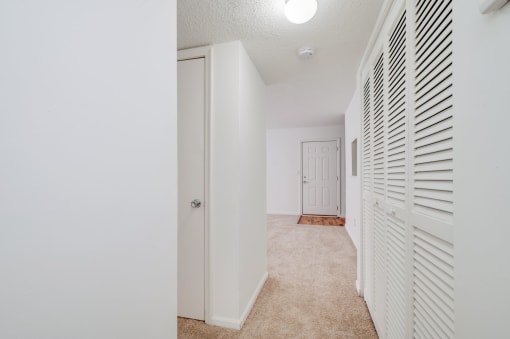a spacious hallway with white closet doors and a door to a bedroom