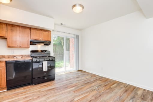 an empty kitchen with wood flooring and black appliances
