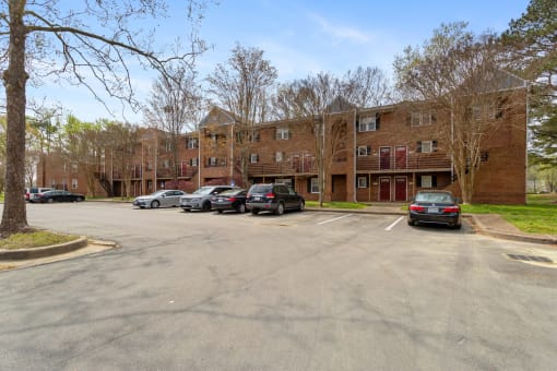 an empty parking lot in front of a brick apartment building