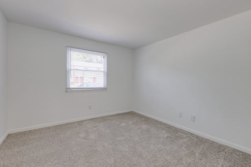 an empty room with white walls and a window